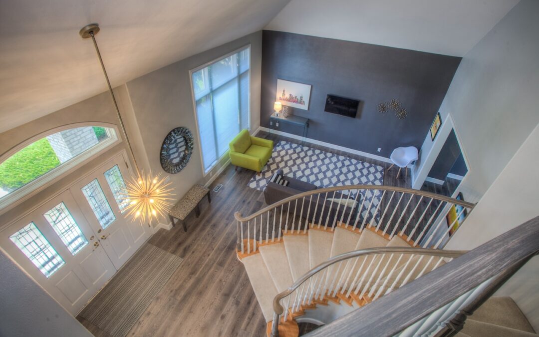 Photo of entryway of open floor plan home with wood flooring and circular stairs. The photo is taken from the second floor landing