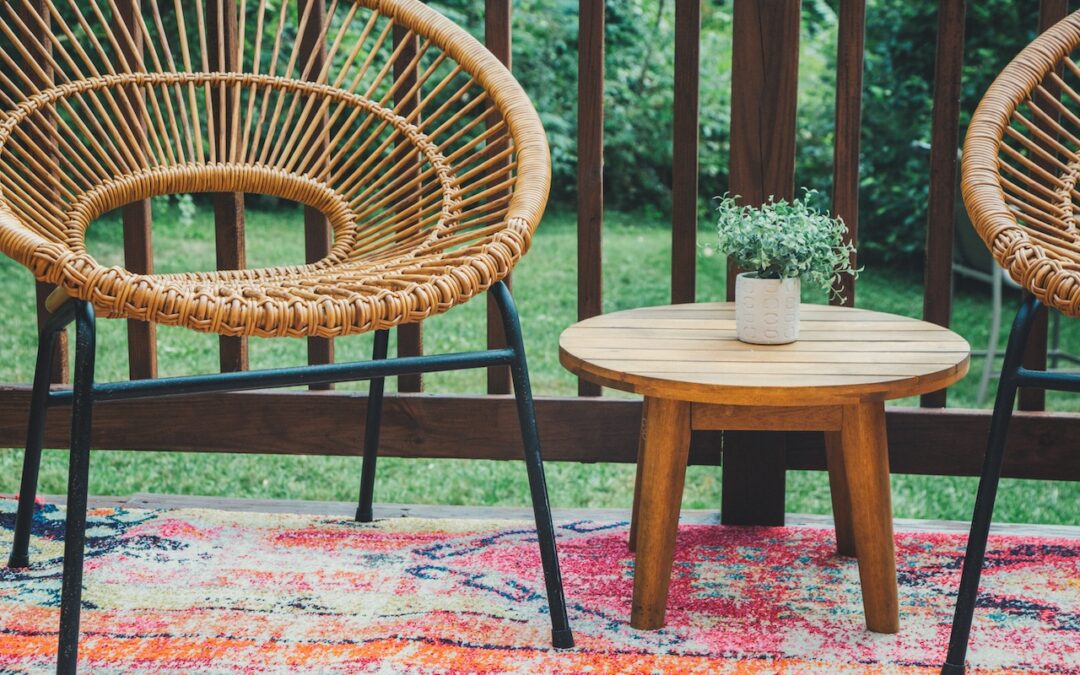 Photo of wicker chairs on outdoor rug of a deck against a wood railing