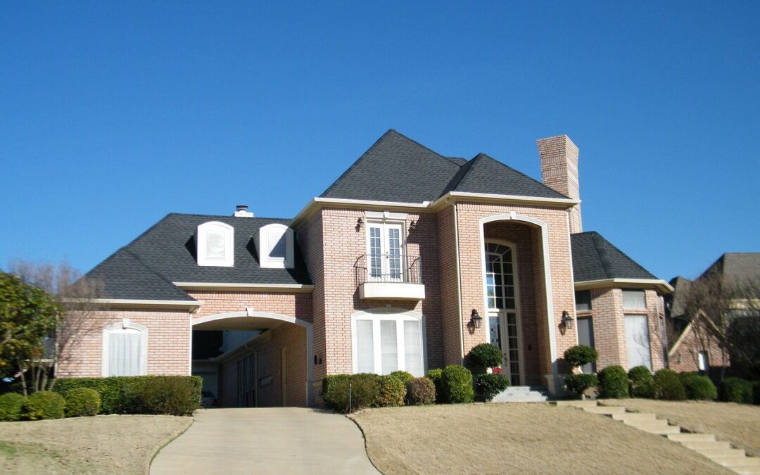 Photo of custom home with covered drive through into interior courtyard style garage, an attached "carriage house and two story home with brick facade