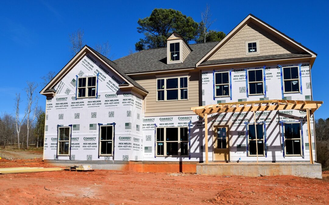 Photo of rear of home under construction. The home has a framed in rear pergola-covered slab patio